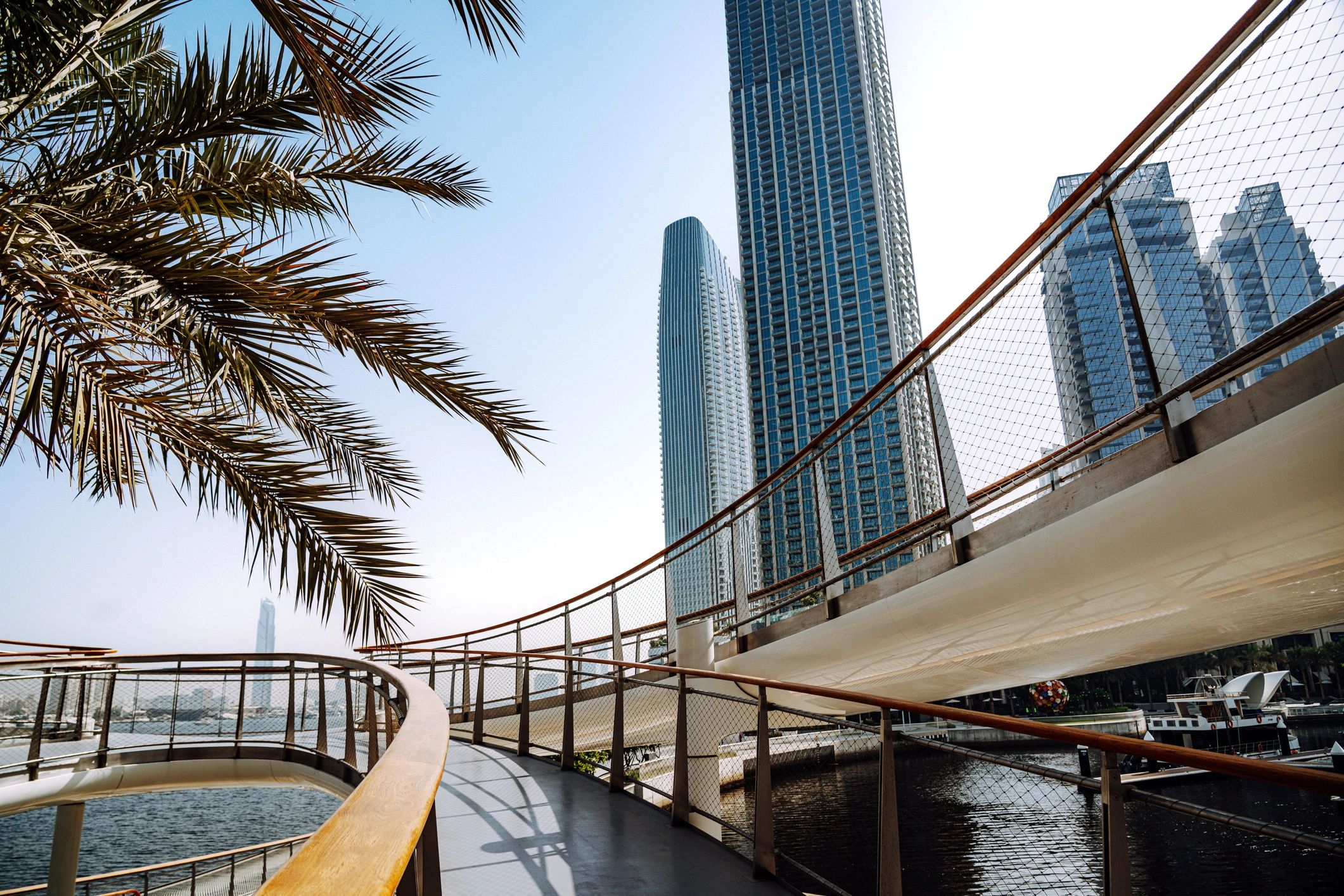 Modern Dubai towers along a waterfront promenade